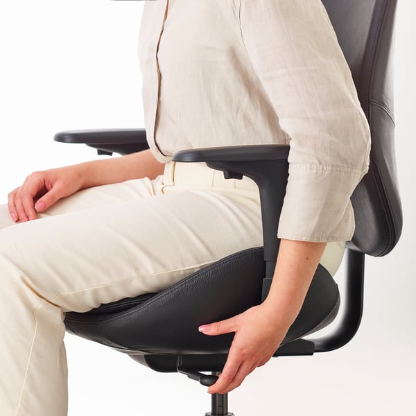 Person sitting in ergonomic office chair with lumbar support and adjustable armrests.