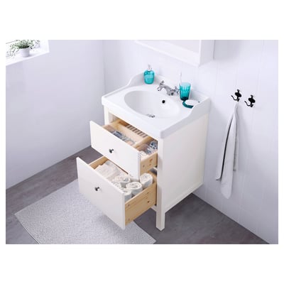 White bathroom vanity with open drawers revealing neatly stacked towels and toiletries. Two handles visible on the wall.