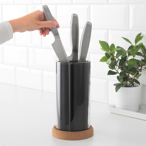 Person grabbing knife from flexible IKEA 365+ block on counter; plant beside.