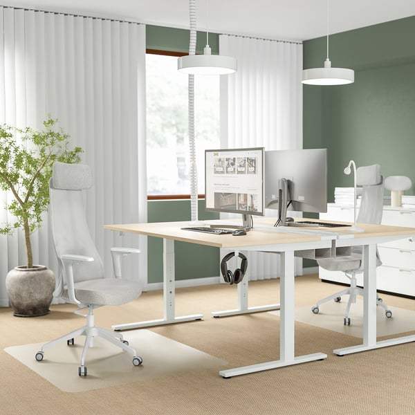 Modern minimalist office with JÄRVFJÄLLET chair, dual monitors, plant, and green accent wall.