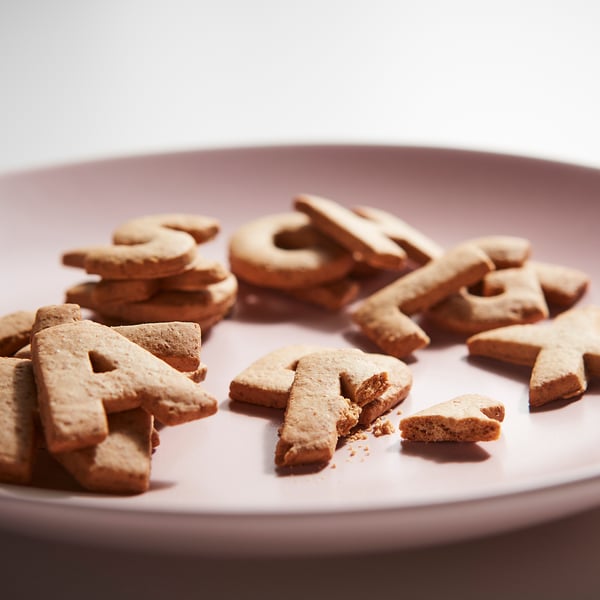 Light brown letter-shaped cookies spell KAFFEREP on a pink plate.