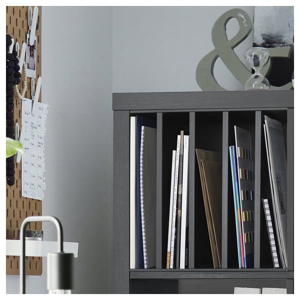 Grey KALLAX shelf with books, against wall, pegboard with notes.