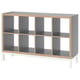 A KALLAX shelving unit in grey with a wooden frame, featuring multiple open compartments and white legs.
