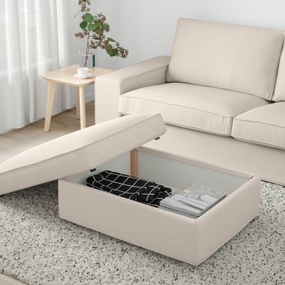L-sofa with lift-top storage and magazines, side table with plant and coffee by window.
