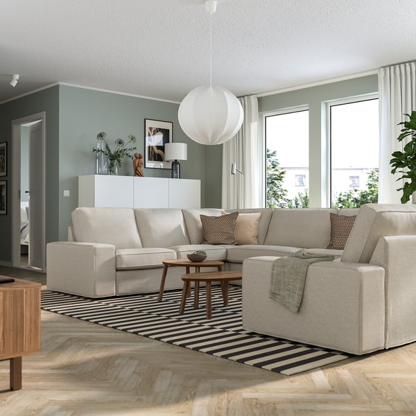 Modern living room with grey KIVIK sectional sofa, black-and-white striped rug, green walls, large windows, and white pendant light.