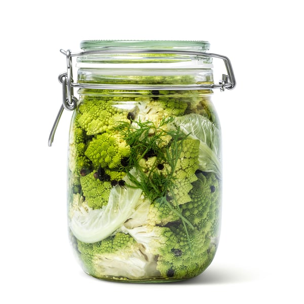 Green veggies in clear glass jar with green seal and metal clasp.