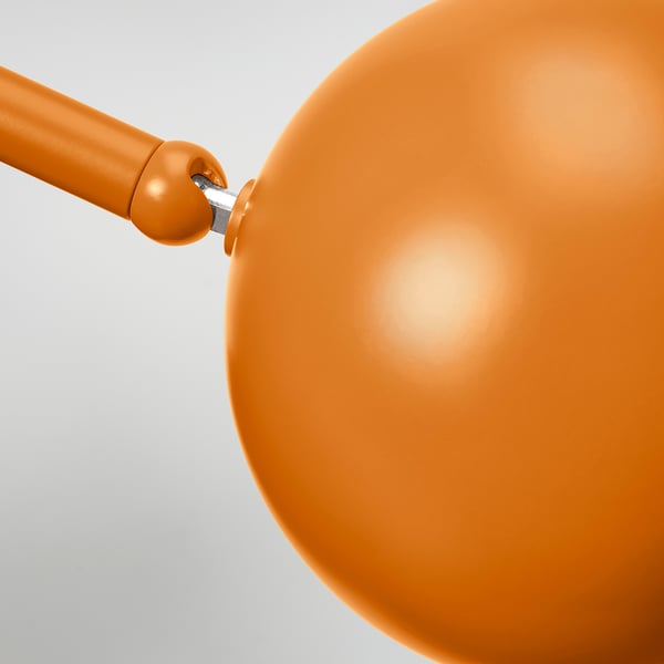 Close-up of a modern orange lamp, showing sleek, adjustable design and matte finish.