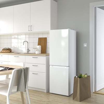 Modern kitchen with LAGAN fridge, glass shelves, led lights. Wooden board, bread, chair, magazines.