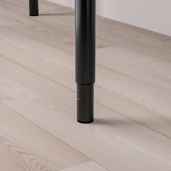Black metal table leg on light wooden floor.