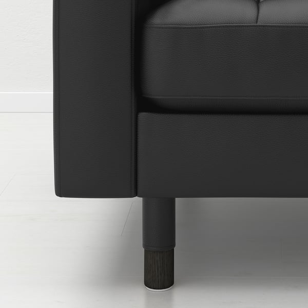 Black leather sofa corner with wooden legs.