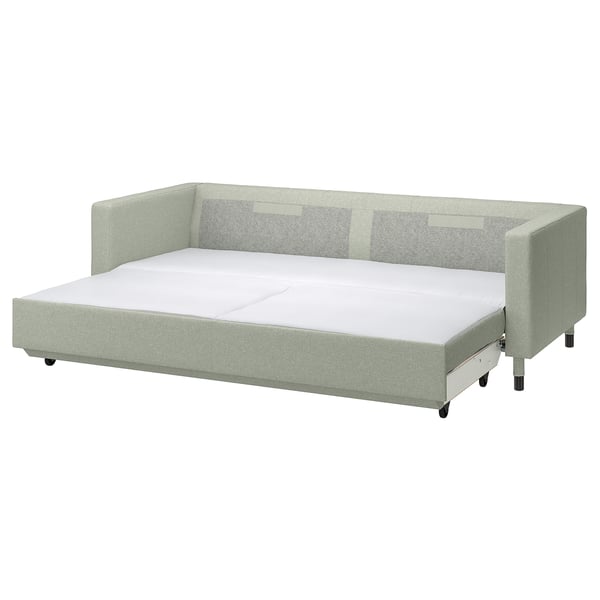 Light green sofa-bed, solid oak legs, firm cushions, converts into bed.