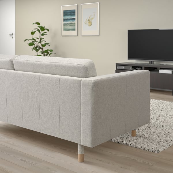 Modern minimalist living room: grey LANDSKRONA sofa, light wood floor, white rug, tv, wall art, plant.