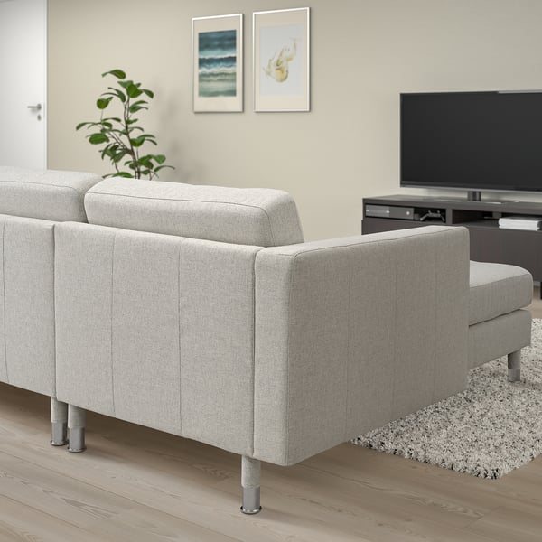 Modern grey 3-seat sofa in living room with metal legs, cushioned seats, rug, tv, plant.