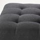 Dark grey upholstered footstool with plush, wavy cushions and tight fabric fit.