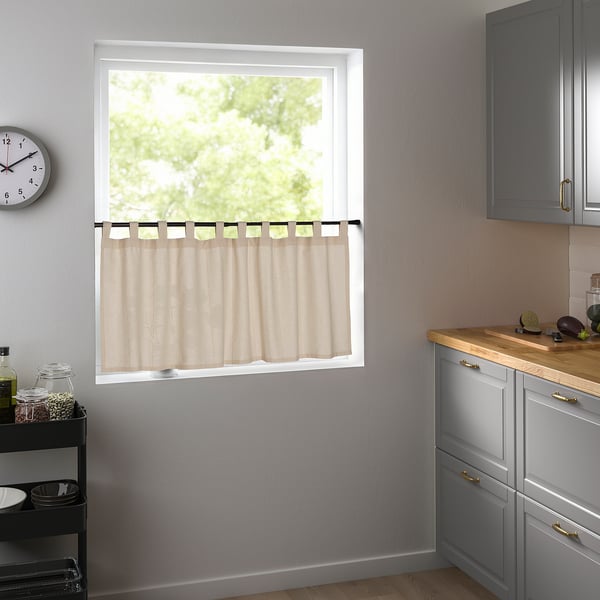 Modern kitchen with beige curtains, grey-blue cabinet, black cart, and clock.