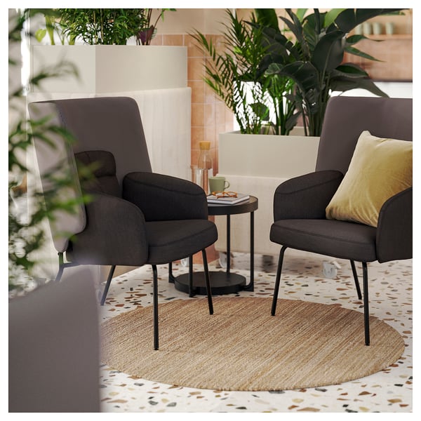 Two grey LOHALS chairs on a jute rug, gold pillow, side table with mug, book, and carafe in a cosy space.