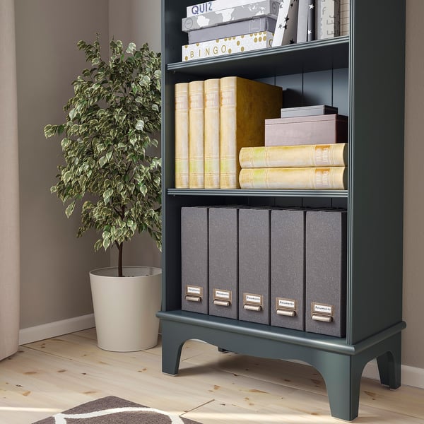 Black bookcase with adjustable shelves holding books, boxes, and a plant.