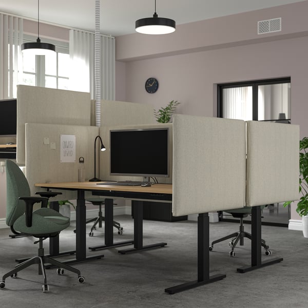Modern office with MITTZON sit/stand desks, acoustic panels, green chairs & large monitor.