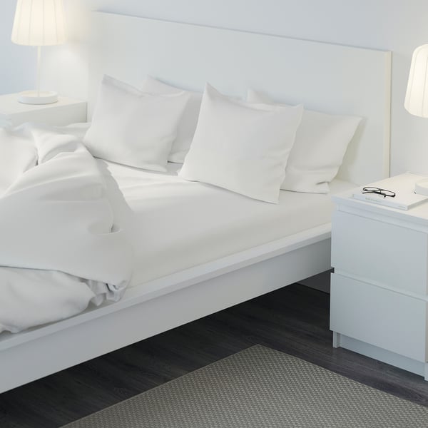 A well-made bed with crisp white sheets, pillows, and a cosy headboard, exuding comfort and warmth.