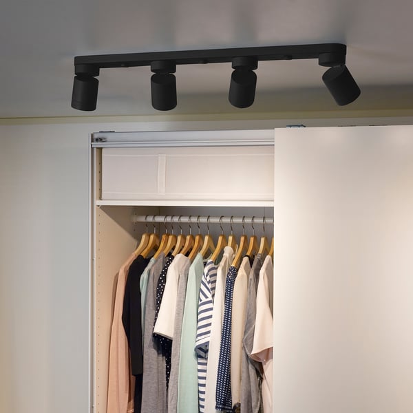 Closet with clothes, lit by adjustable, black NYMÅNE spotlights.