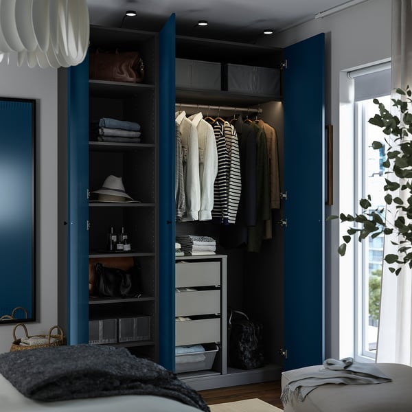 Modern blue PAX wardrobe with neatly organised clothes, shelves, and drawers, illuminated interior, and stylish decor.