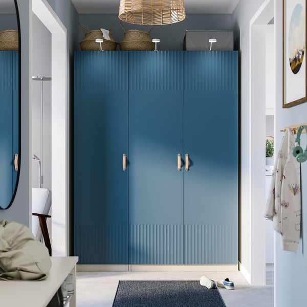 Modern entryway with blue PAX wardrobe, textured doors, wicker baskets, woven light, shoe rack, hooks.