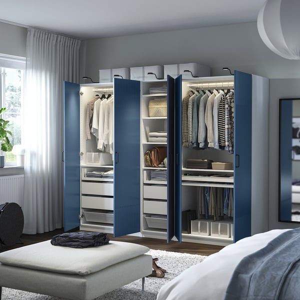 Open blue PAX wardrobe showing clothes, shelves, drawers, and internal lighting.