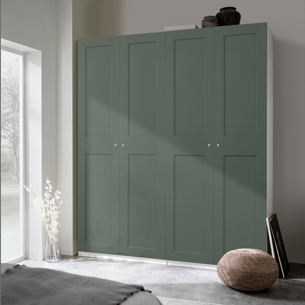 Large green PAX wardrobe against wall, oversized in room, with decorative vases on top, plant beside, and woven stool front.