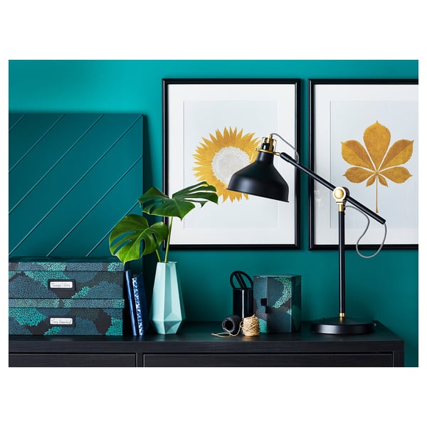 Stylish black desk lamp, RANARP, against teal wall with art prints. Adjustable, modern, sleek design, perfect for reading.