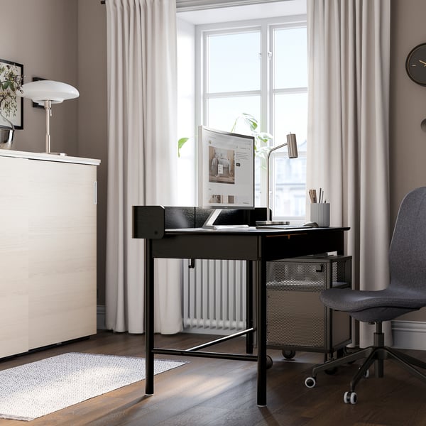 Black desk with oak veneer, drawer, chair, lamp, window.