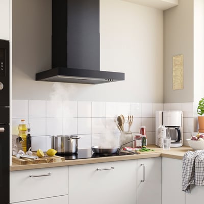 Modern kitchen with black RULLBO hood, white tiles, white cabinets, and wooden countertop. The hood is sleek and fits seamlessly above the stove.