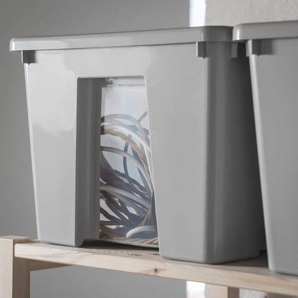 Three grey stackable storage boxes on shelf.