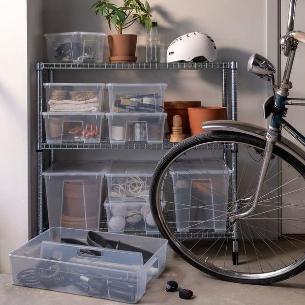 Clear plastic storage boxes with items, bike, plant, helmet.