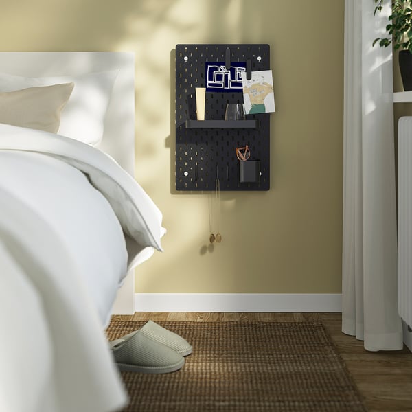 Bedroom with SKÅDIS pegboard for notes, keys, and a cup. Slippers and rug beside bed.