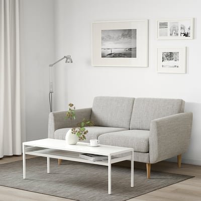 Modern living room with grey SMEDSTORP sofa, white table, black-and-white prints, vase, and cup.