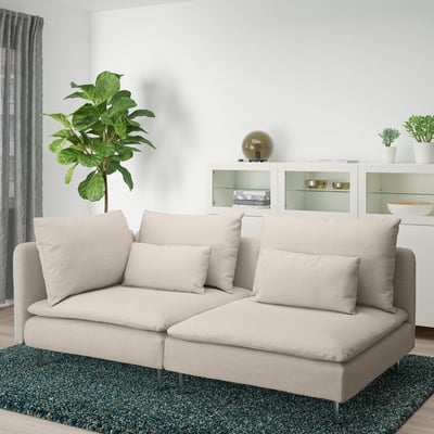 Grey ikea SÖDERHAMN corner sofa in modern living room with green rug, plant, and white cabinet.