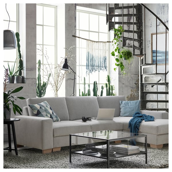 Modern living room with SÖRVALLEN sofa, glass table, and metal stairs. Decorated with cacti and hanging plants, boho chic style.