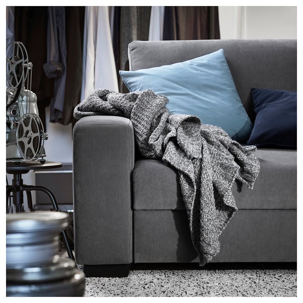 Modern grey sofa with blue pillows and grey blanket, vintage film reel decoration.