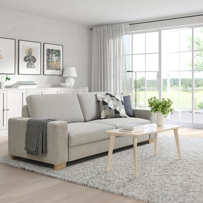 Living room with grey sofa, throw pillows, blanket, coffee table with books & greenery, white cabinet with books & lamp, bright & airy.