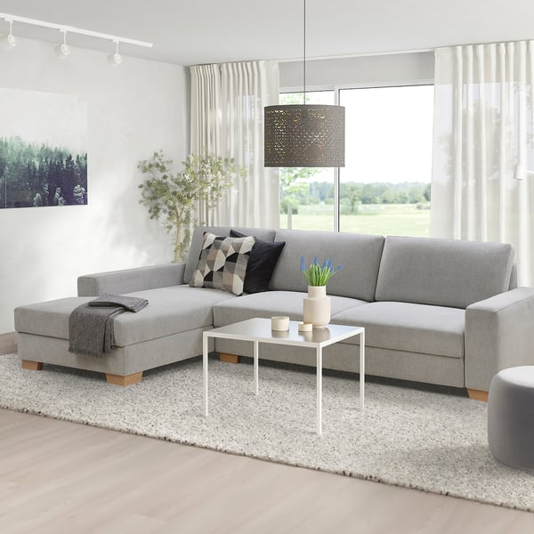 Grey SÖRVALLEN sofa with a modern design. Its large, with a white coffee table and decor in a minimalist living room.