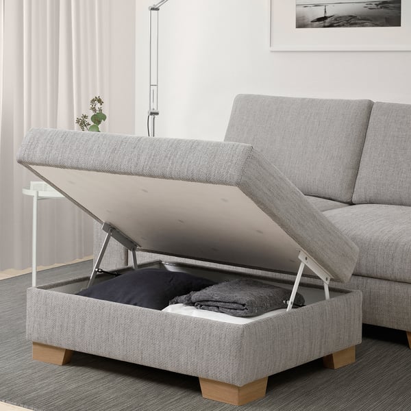 Modern grey sofa with lifting storage compartment, revealing folded blankets inside.