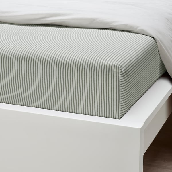 Crisp green and white striped fitted sheet on a thick mattress, showcasing quality cotton and elastic edges.