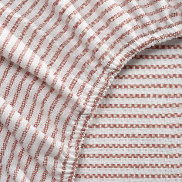 Striped sheet in red and white, folded neatly, showcasing quality cotton and elastic edges.