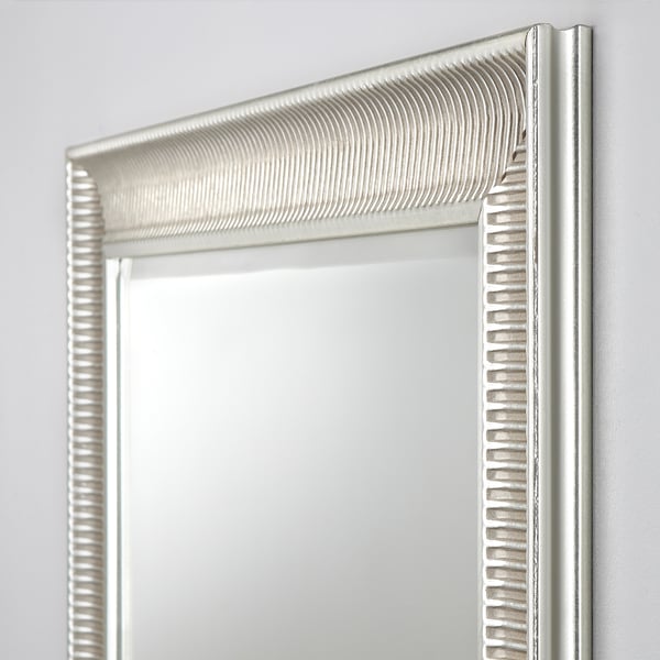 Ornate mirror with intricate textured frame, reflecting crisply. Shows subtle signs of ageing, adding vintage charm. Mounted securely on a plain wall.