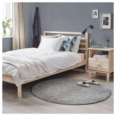 Minimalist bedroom with white bedding, grey rug, wooden furniture, and blue walls. A cosy, modern design.