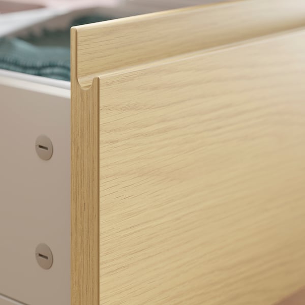Close-up of light wood drawer edge with metal handle.
