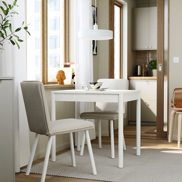 Modern white TONSTAD dining table, extends from 2 to 4 seats, sleek design, with two padded chairs.