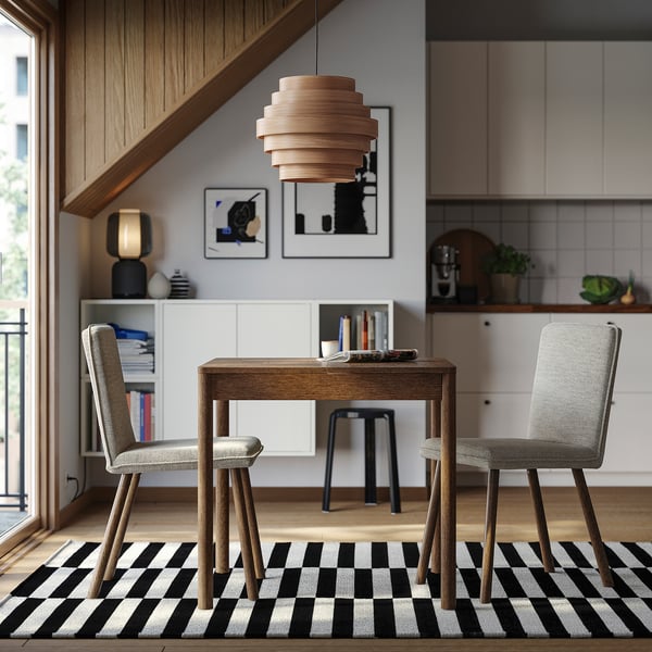 Modern home office with grey chairs, wooden desk, rug. Pendant light, art on walls, bookshelf, natural light.
