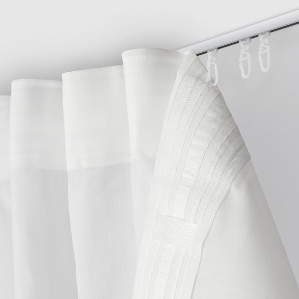 A bright white shower curtain hangs from three hooks, serving as a bathroom divider.