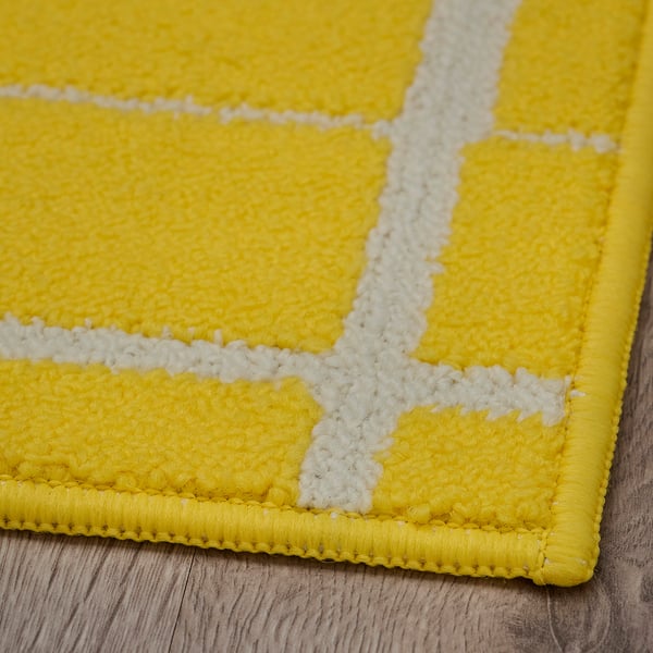 Bright yellow geometric rug with white lines, displayed on wooden floor. Soft texture, even stitches, high quality.